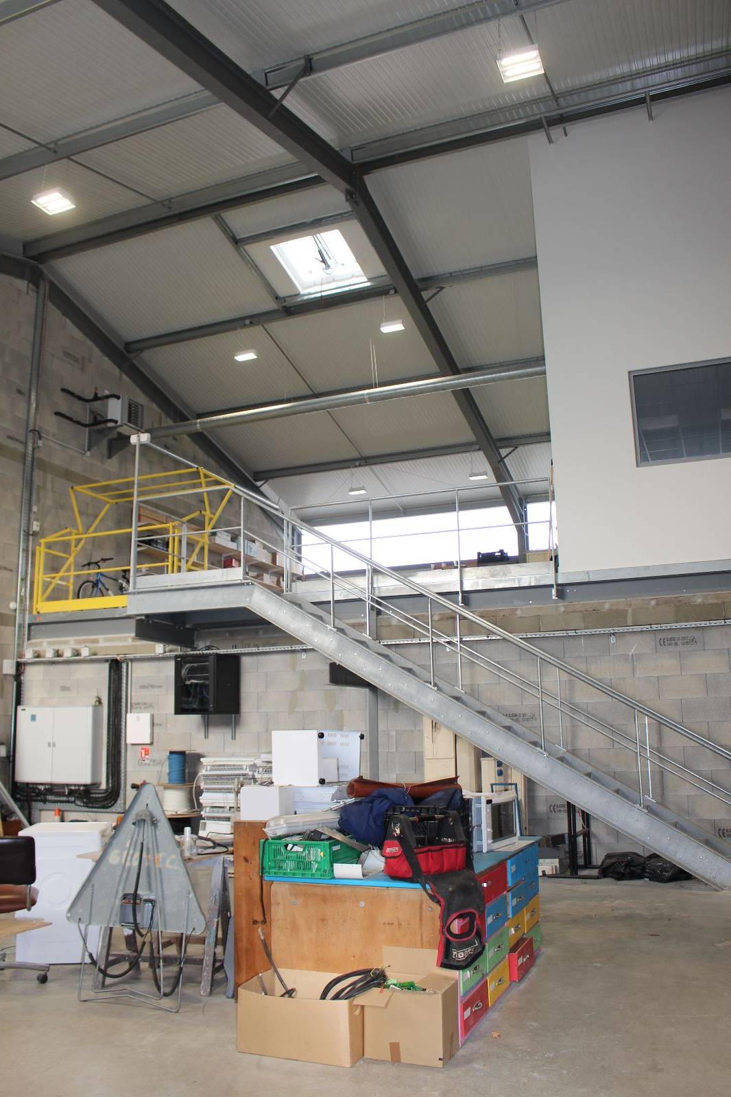 Polycarbonate sur porte sectionnelle, atelier en double hauteur et escalier métallique,